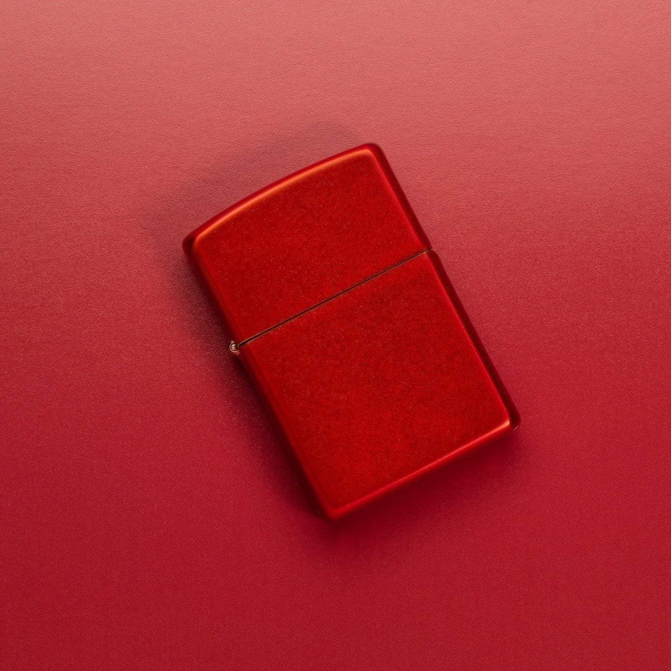 Lifestyle image of Metallic Red Windproof Lighter laying on a red surface